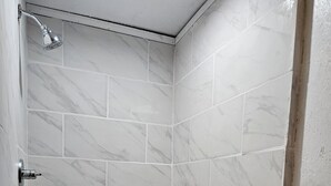 A small, white-tiled shower with a handheld showerhead. - Private 1 room studio near rhe lake (Burnet)