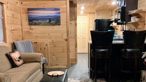 Ein gemütliches Blockhaus mit Holzvertäfelung, einer Essecke mit Stühlen und einem Tisch sowie einem Bild an der Wand.