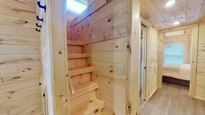 Ein Holzinnenraum mit einer Treppe zu einem Erker, einer Tür zu einem Schlafzimmer und einem Fenster mit Jalousien.