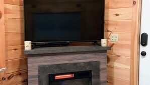 Ein Holzhütten-Innenraum mit einem Fernseher auf einem Kaminvorsatz über einem Kamin.