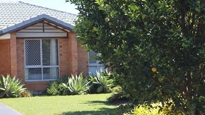 A residential building with a tiled roof, a brick facade, and a window with a lattice design.