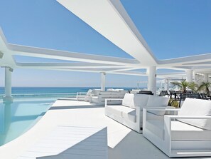 A modern outdoor pool area with white lounge chairs and a clear view of the ocean. - Global Vacacional: Modern flat with two terraces with sea and mountain views (Canet d´en berenguer)
