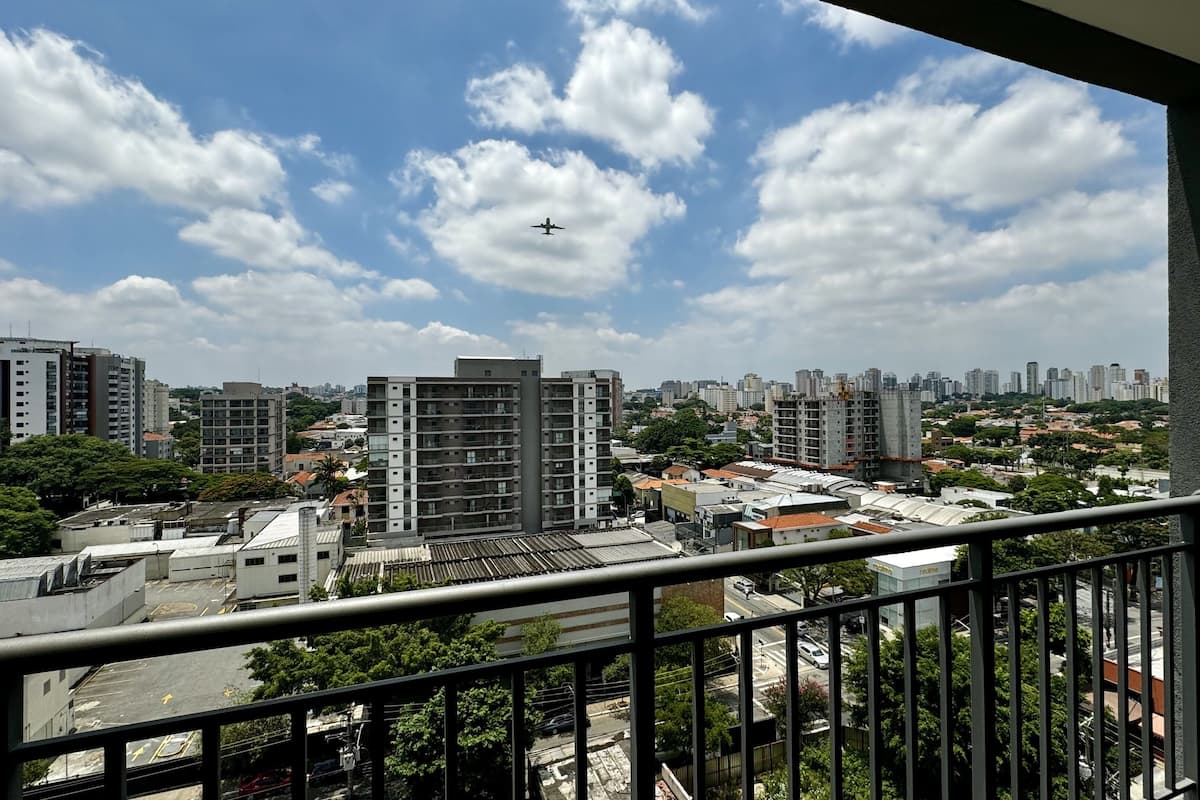 A cityscape with high-rise buildings, a clear sky, and a distant airplane.