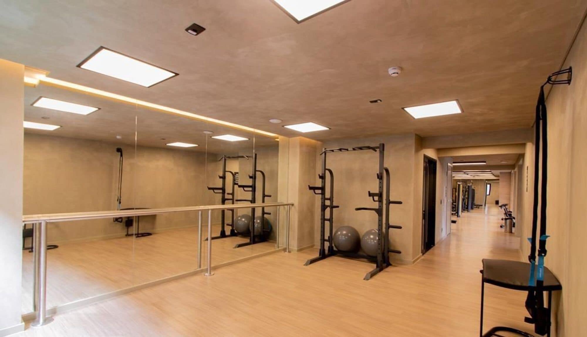 Un gimnasio con paredes de espejo, equipamiento de ejercicio y suelo de madera.