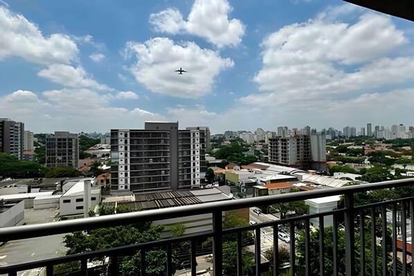 Une vue urbaine avec des bâtiments modernes, un ciel dégagé et un avion qui vole au-dessus.