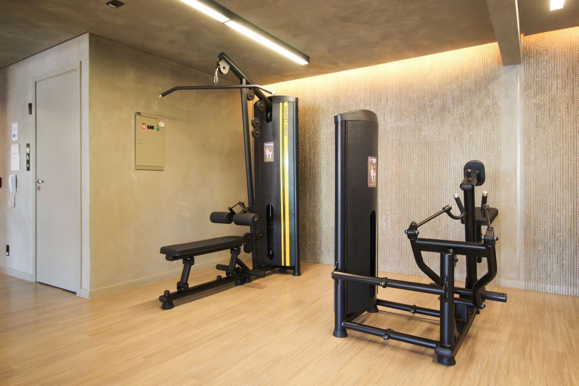 Ein Fitnessraum mit Trainingsgeräten, einer Bank und einer an der Wand befestigten Klimmzugstange.