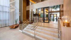 Un hall d’hôtel moderne avec un escalier, des portes vitrées et un espace d’accueil.