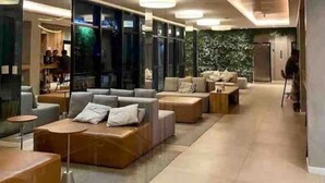 Un espace de détente moderne, avec des canapés, des tables et un grand mur végétalisé.