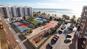 Un immeuble de grande hauteur doté d’un court de tennis, d’un parking et offrant une vue sur la plage.