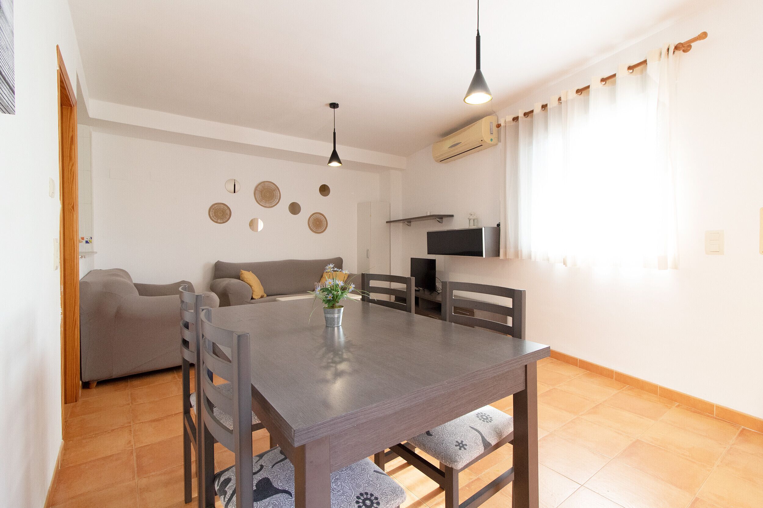 Een eethoek met een tafel en stoelen, een bank, een televisie en een wand met decoratieve borden.