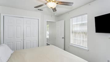Relax in this serene bedroom with a comfortable bed, ceiling fan, and flat-screen TV.