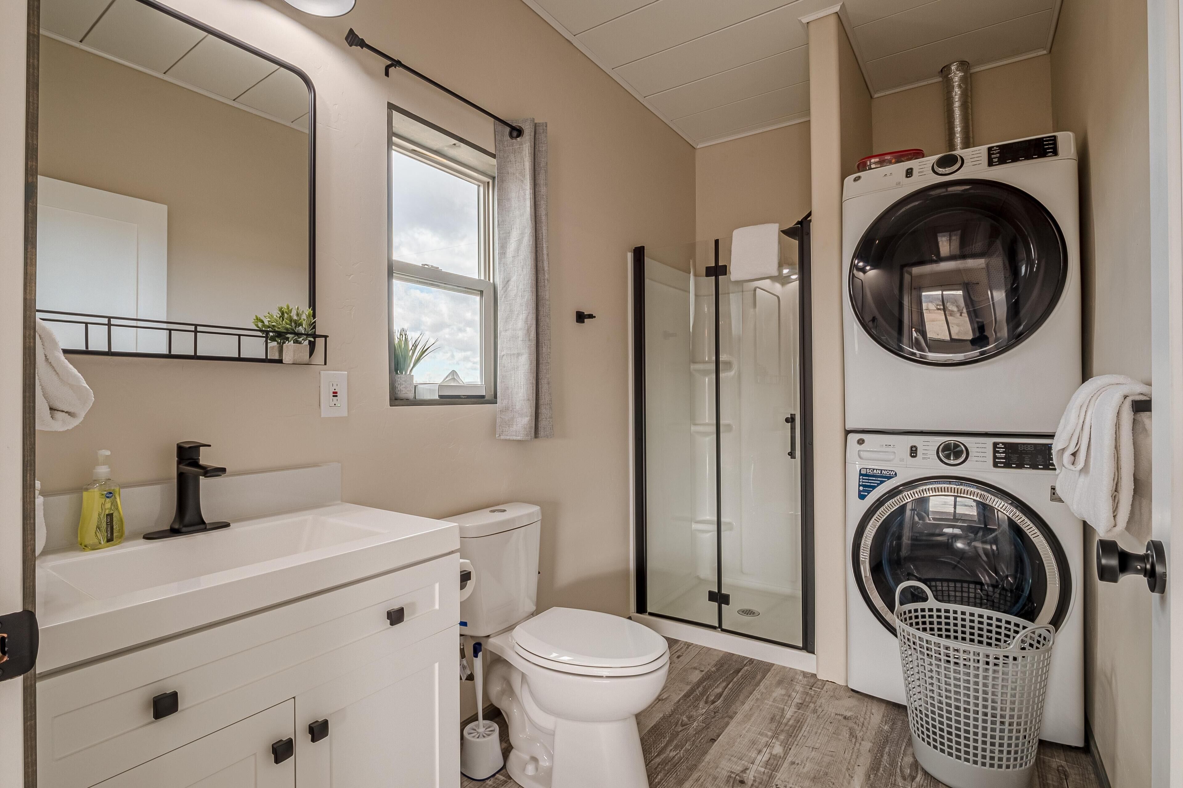A compact bathroom with a sink, toilet, and a glass-enclosed shower.