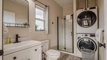 A compact bathroom with a sink, toilet, and a glass-enclosed shower.