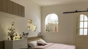 Un dormitorio con cama, escritorio, silla, mesita y ventana.