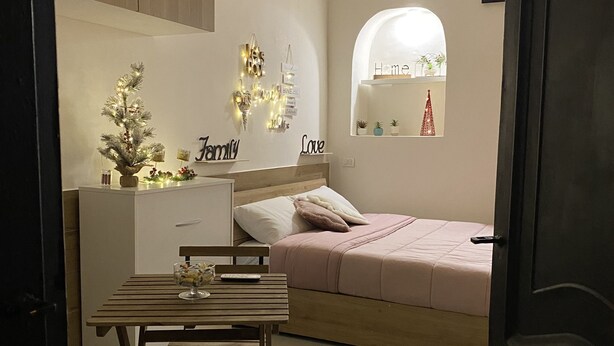 Un dormitorio moderno con cama, mesita de noche, escritorio pequeño y silla. Se ve una ventana con vistas al exterior.