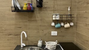 Una cocina moderna con un lavamanos de acero inoxidable, encimera negra y un refrigerador compacto.