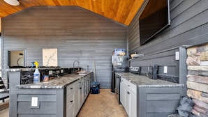 A compact kitchen with dark wood cabinets, granite countertops, and a stone accent wall. - NEW 6 Bedrooms - Two houses and a pavillion on Chickamauga Lake with new dock
 (Decatur)
