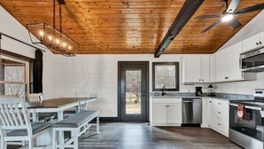 A modern kitchen with white cabinets, a built-in oven, and a dining area with a bench and chairs. - NEW 6 Bedrooms - Two houses and a pavillion on Chickamauga Lake with new dock
 (Decatur)
