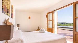A bedroom with a bed, a bedside table, a lamp, and a painting on the wall. - Villa Dalt S Era with Mountain View, Wi-Fi, Air Conditioning, Pool & Garden (Santa Gertrudis de Fruitera)