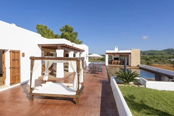 Una villa con piscina, mobiliario exterior y una pérgola.