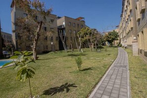 A pathway leading to a building with a pool on the left. - New! Bamboo El Encanto pool & eace (Jiutepec)