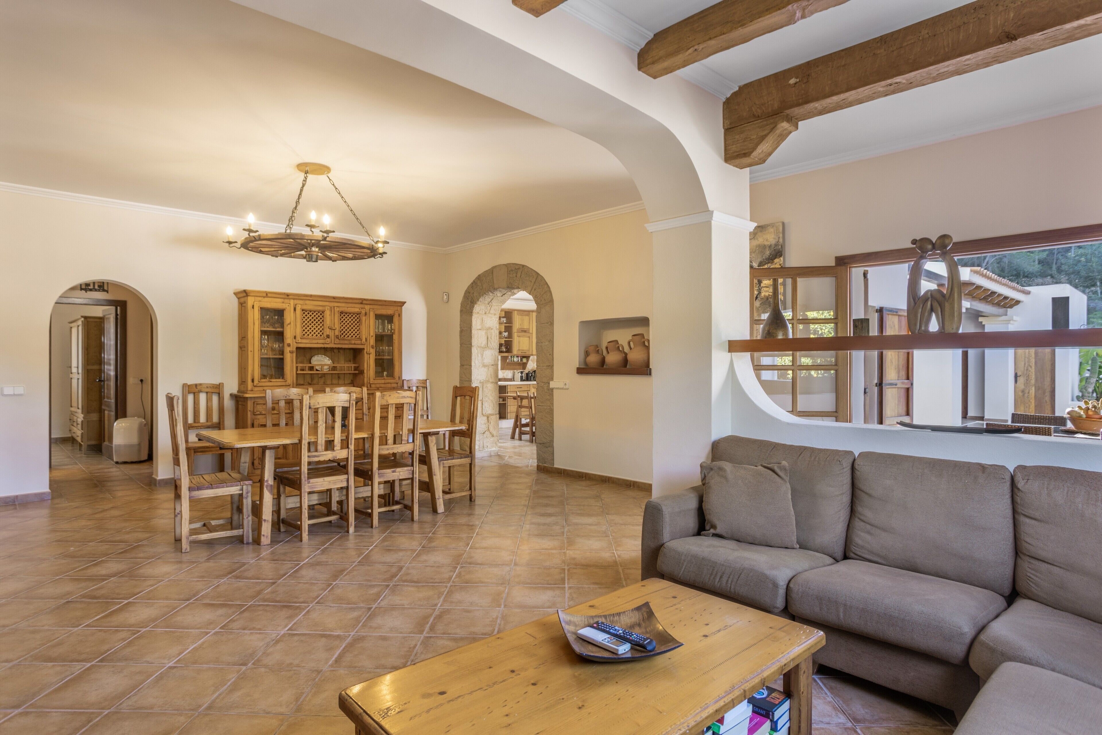 Amplia sala de estar con una mesa de comedor de madera, un sofá y un ventanal con vistas.