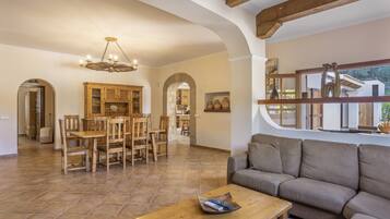 Amplia sala de estar con una mesa de comedor de madera, un sofá y un ventanal con vistas.