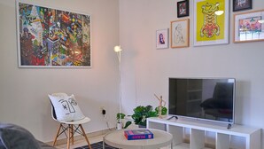 Ein modernes Wohnzimmer mit großem Flachbildfernseher, einer weißen Unterhaltungseinheit, einem runden Couchtisch und einem grauen Sofa.