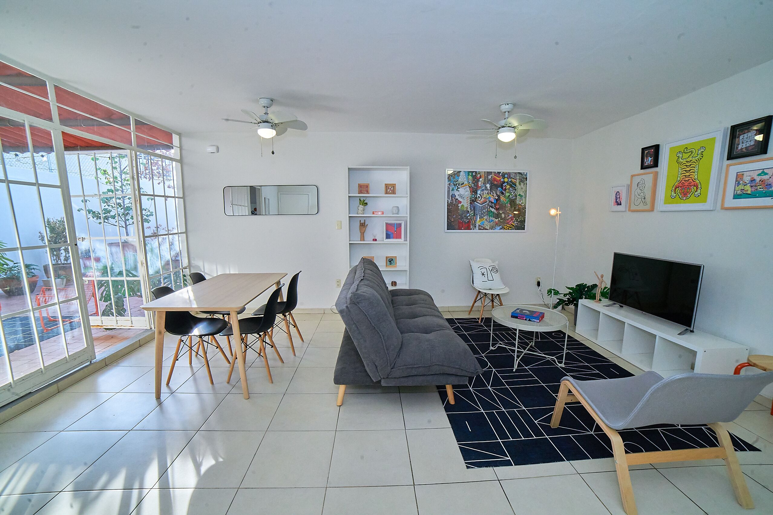 Un salon moderne comprenant un canapé, une table à manger, des chaises et un téléviseur.