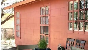 Uma área de refeições com uma mesa e cadeiras, um recipiente decorativo com uma planta e uma janela com detalhes em metal.