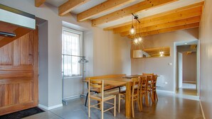 Ein Essbereich mit Holztisch und -stühlen, einer Holzbalkendecke und Pendelleuchten.
