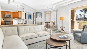 A modern hotel room with a living area, kitchenette, and a balcony with a view.