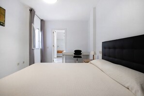 A hotel room with a bed, a desk, and a chair.