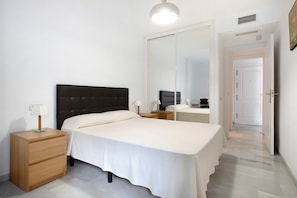 Ein Schlafzimmer mit Bett, Nachttischen, einem Spiegel und einem Kleiderschrank.