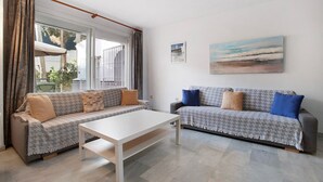 A living room with two sofas, a white coffee table, and a painting on the wall. - Apartment "Don Juan Manuel" with Shared Pool & Wi-Fi (Torremolinos)