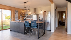 A modern kitchen with a central island, bar stools, stainless steel appliances, and pendant lighting. - Holiday Home 'Gite Ty Laouen' with Private Terrace and Wi-Fi (SARZEAU)