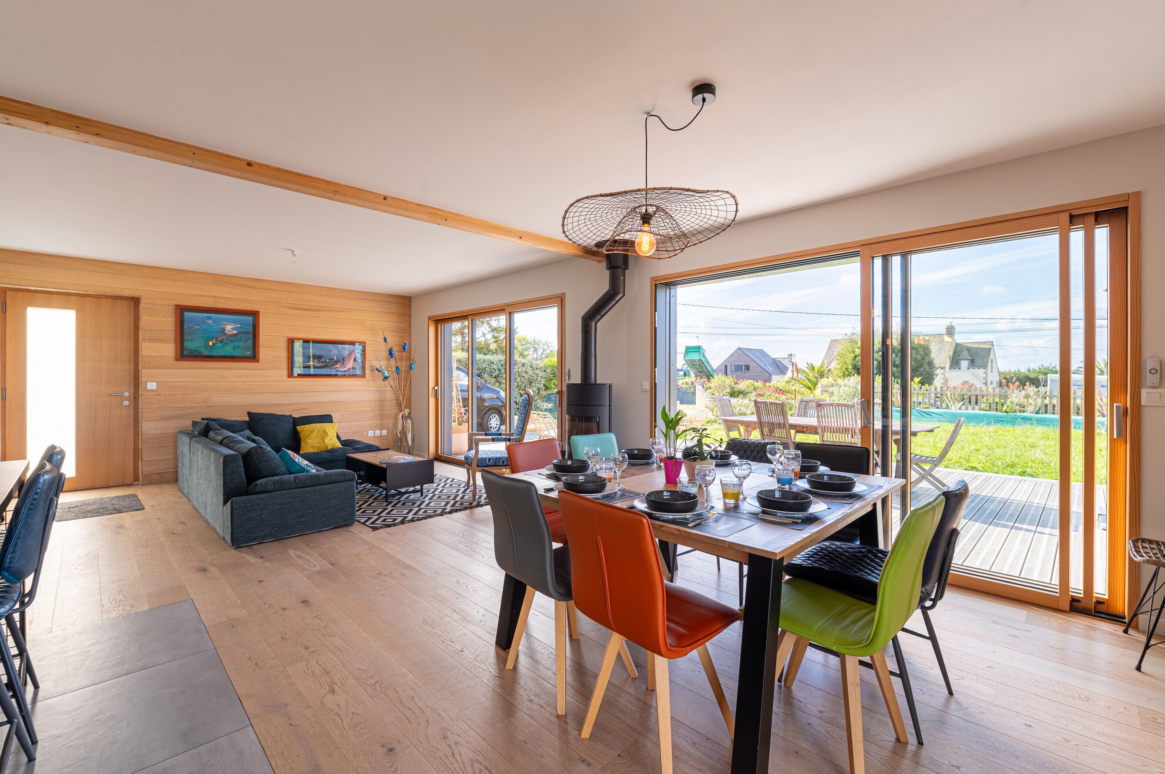 Un espace de vie moderne comprenant un coin repas, un plancher en bois et de grandes fenêtres.