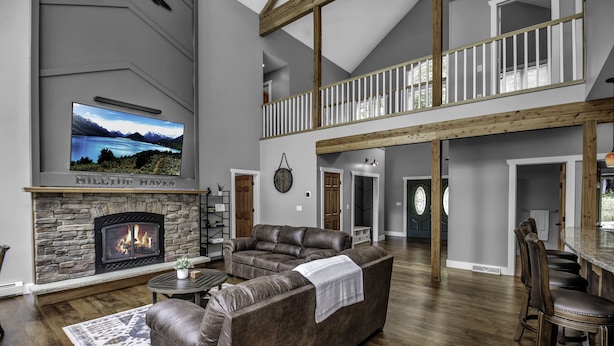 A spacious living room with a stone fireplace, leather sofas, and a large flat-screen TV.