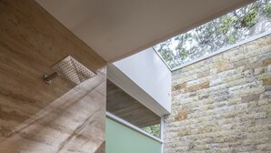 A modern bathroom with a shower, a window, and a small garden area with plants.