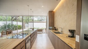 A modern kitchen with a large island, wooden cabinets, and a view of the outdoors.