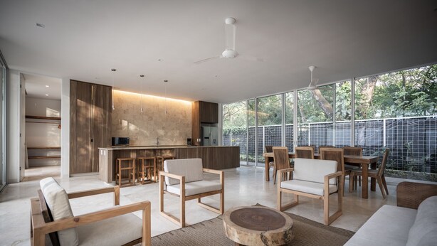 A modern living room with a large window, wooden furniture, and a kitchen area.