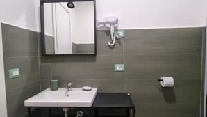 A bathroom with a sink, mirror, towel dispenser, and toilet paper. - The Fondaco At The Historical Archives (Napoli)