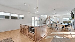 Una cocina amplia con una isla central, armarios de madera y un comedor con sillas.