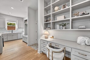 Una cocina moderna con armarios blancos, horno empotrado y ventana con vistas al verdor.