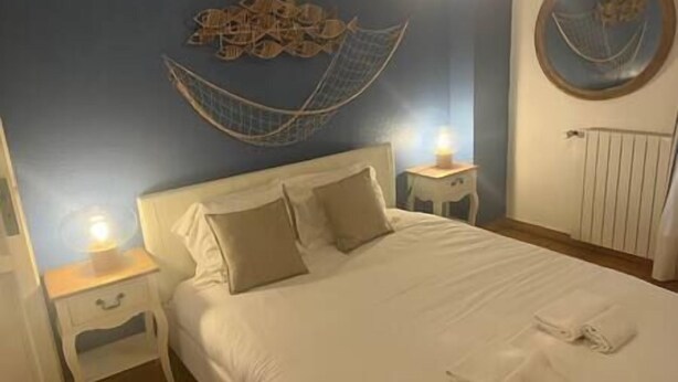 A bedroom with a bed, two bedside tables, a wall decoration, and a radiator.