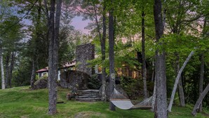 A rustic cabin surrounded by trees, a hammock, and a stone staircase. - Lakefront Cabin/ 314`  Shoreline (Stoddard)