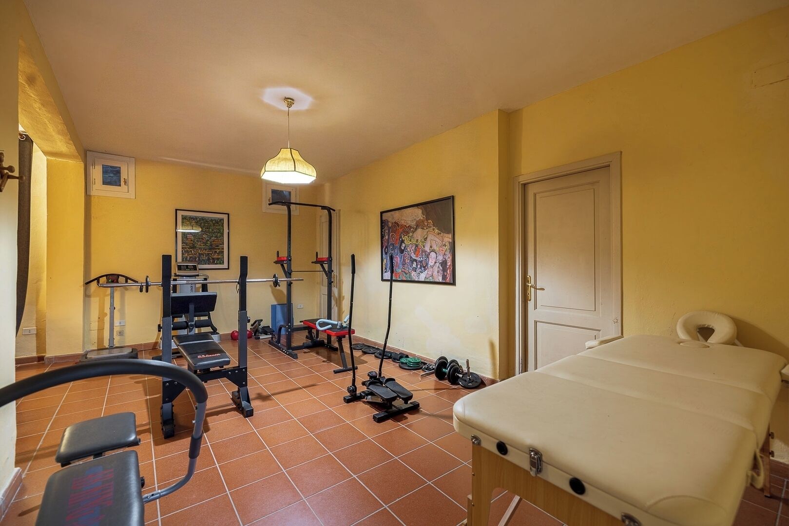 A room with a bed, exercise equipment, and a door.