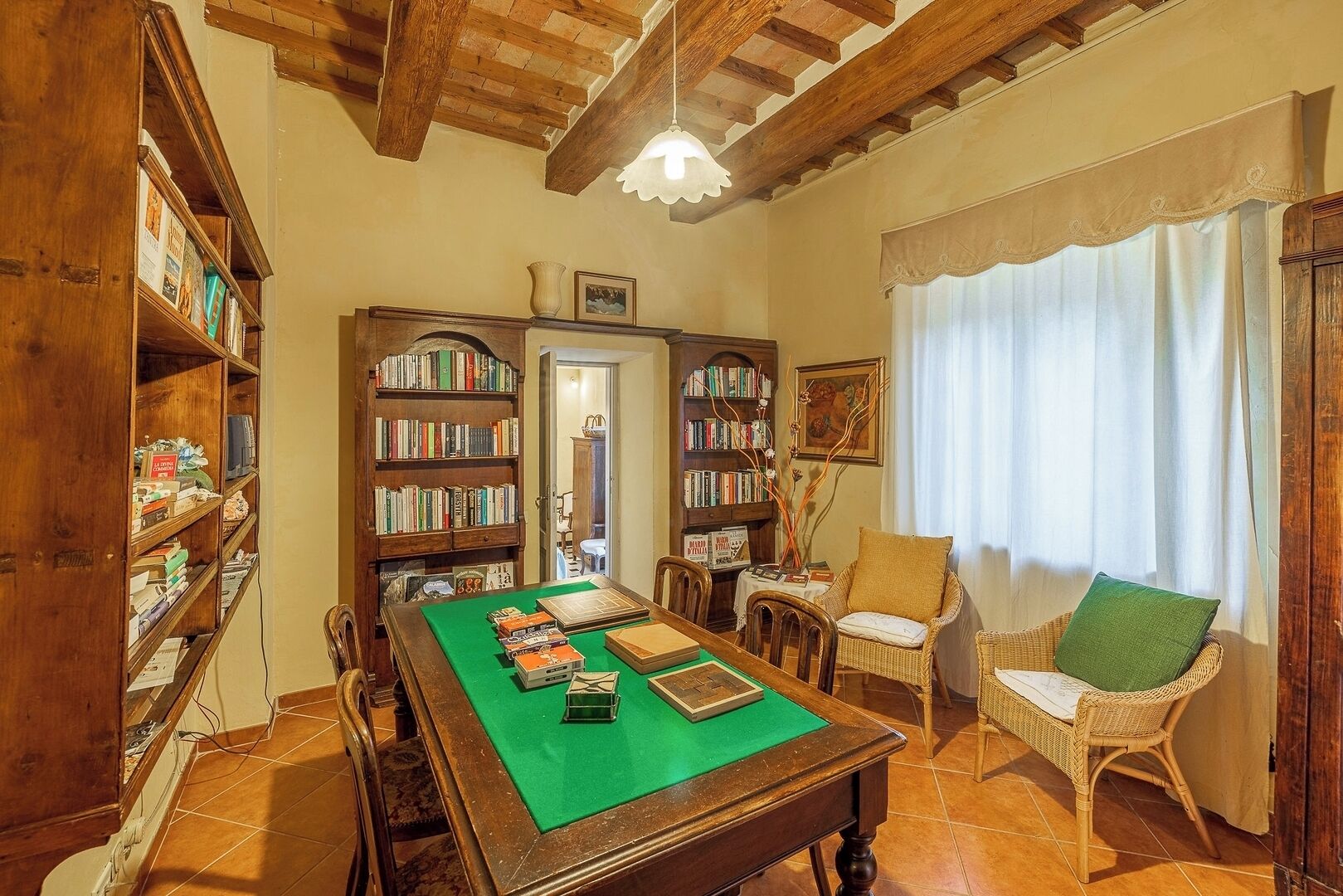 Une pièce avec une table de billard, des étagères à livres, des fauteuils en osier et un plafond en bois.