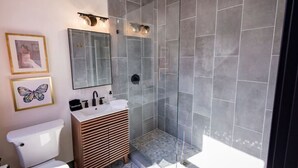 Une salle de bain moderne équipée de toilettes, d’un lavabo, d’un miroir et d’une douche.