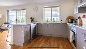 Una cocina moderna con armarios grises, lavavajillas de acero inoxidable y piso de madera.